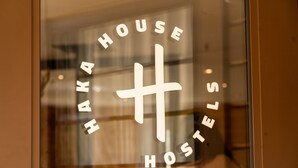 A glass window with the text "Haka House Hostels" and a stylized 'H' logo.