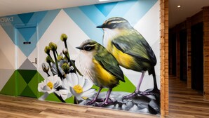 Un mural con pájaros y flores en una pared, con un diseño geométrico y piso de madera.