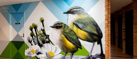A mural of birds and flowers on a wall with a geometric pattern and a wooden floor.