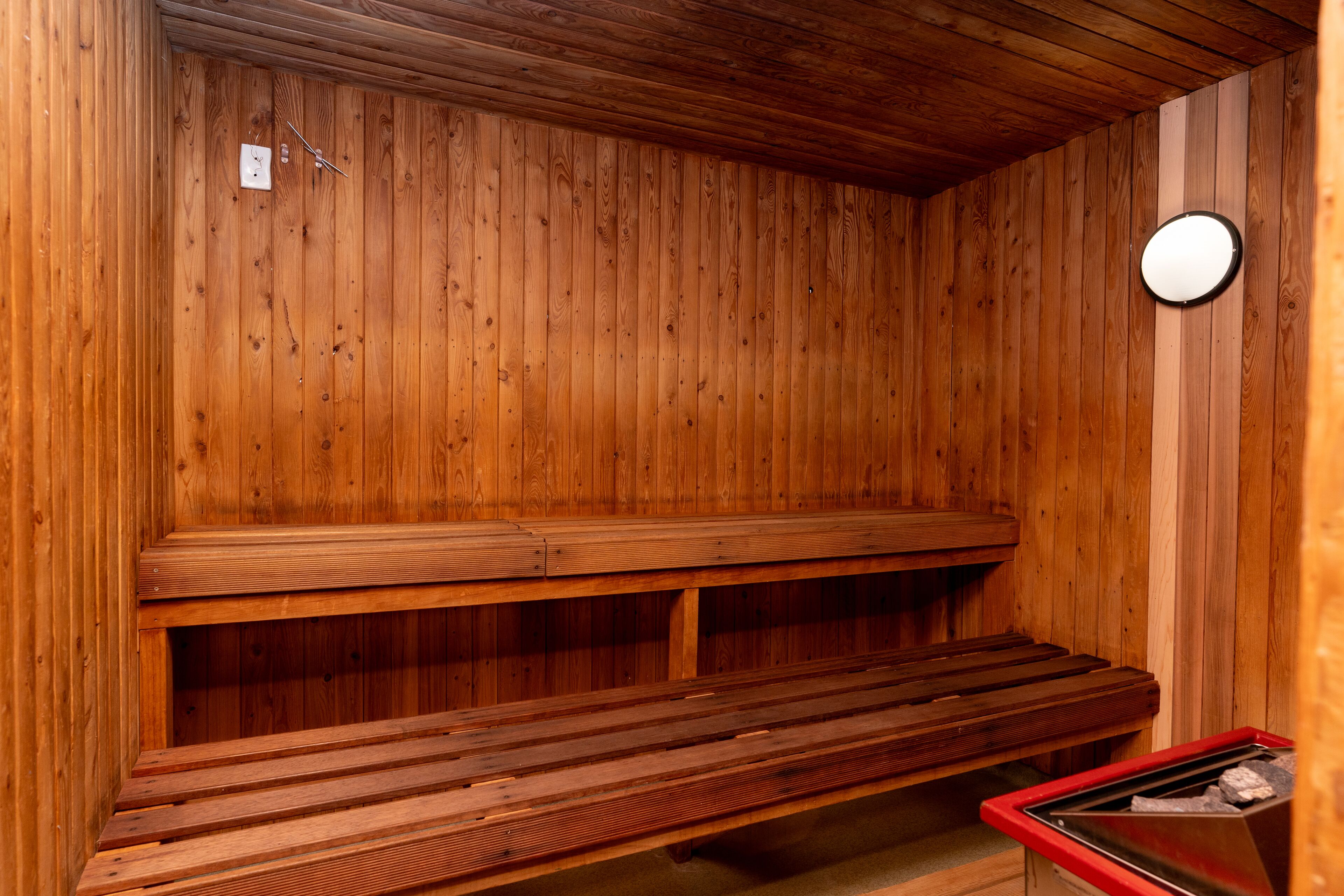 A wooden sauna with benches and a heater.