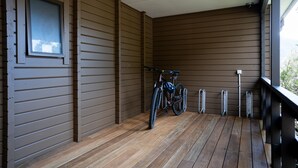 Un porche de madera con una bicicleta apoyada en la pared.