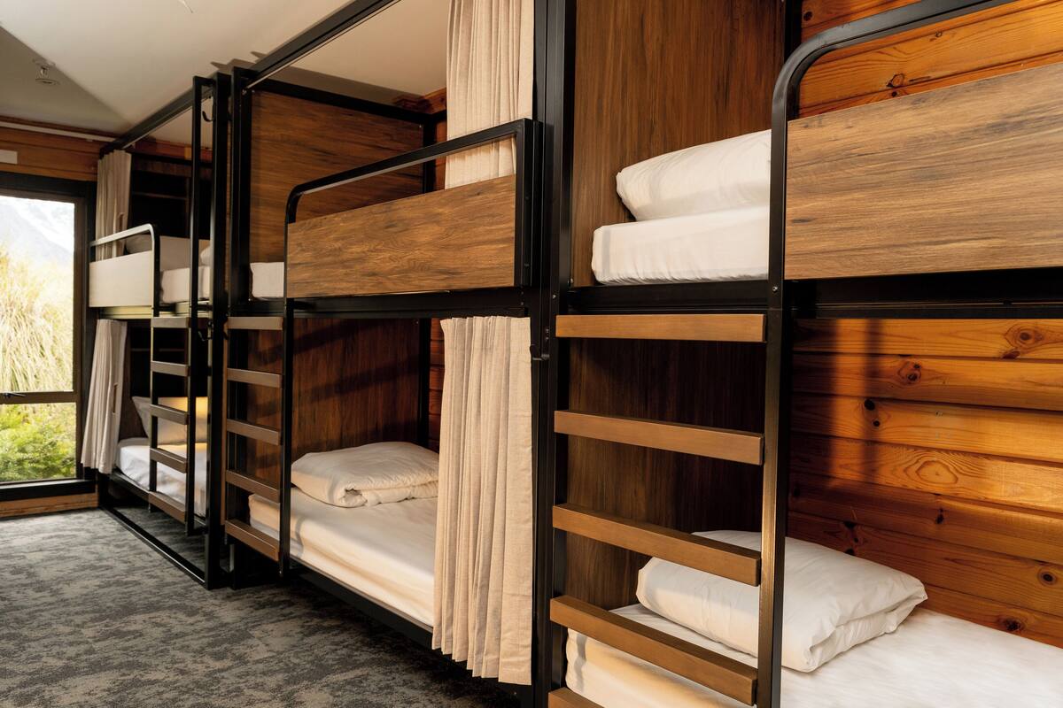 A bunk bed room with wooden walls and a window.