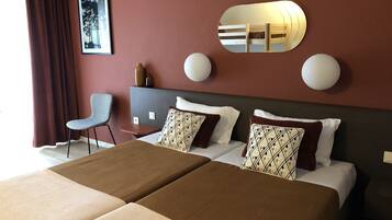 Habitación de hotel con dos camas, un escritorio, una silla y un espejo grande.