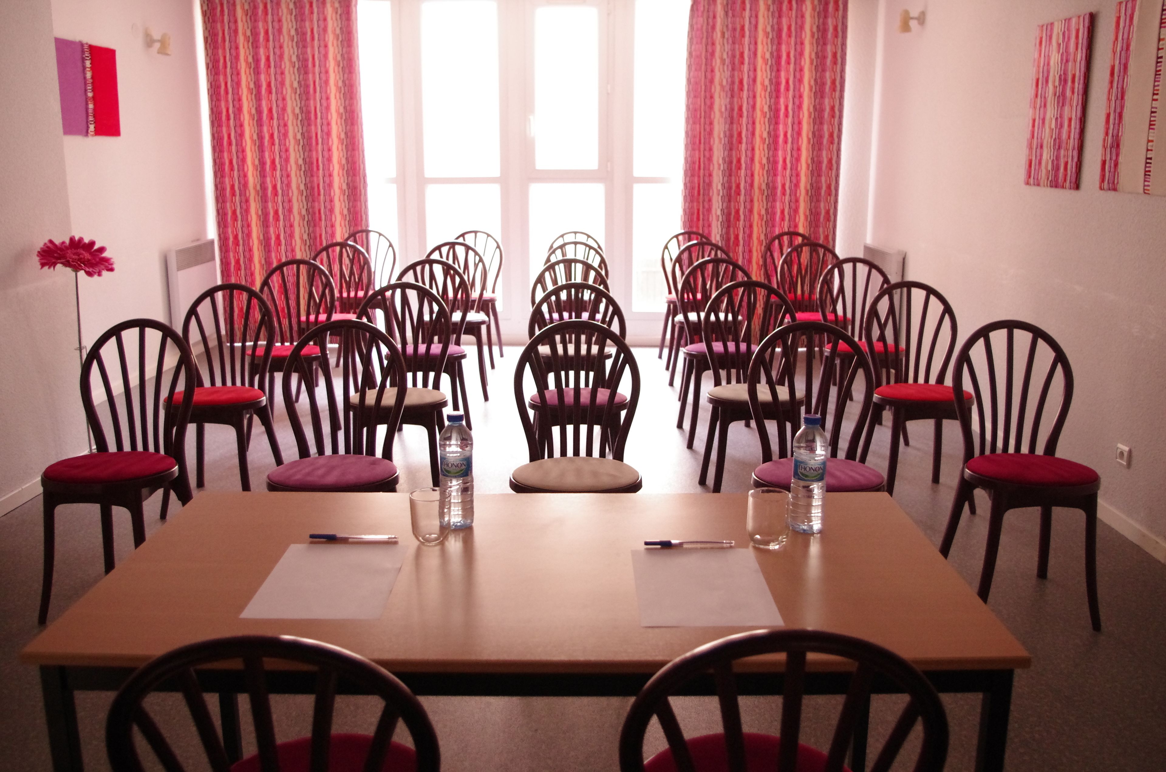 Una sala de conferencias con una larga mesa, varias sillas y un ventanal con cortinas.