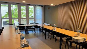 Ein Konferenzraum mit einem langen Tisch, Stühlen, einem Projektor und Wasserflaschen.
