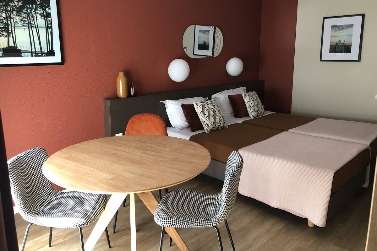 A hotel room with a bed, two bedside tables, a round dining table, and two chairs.
