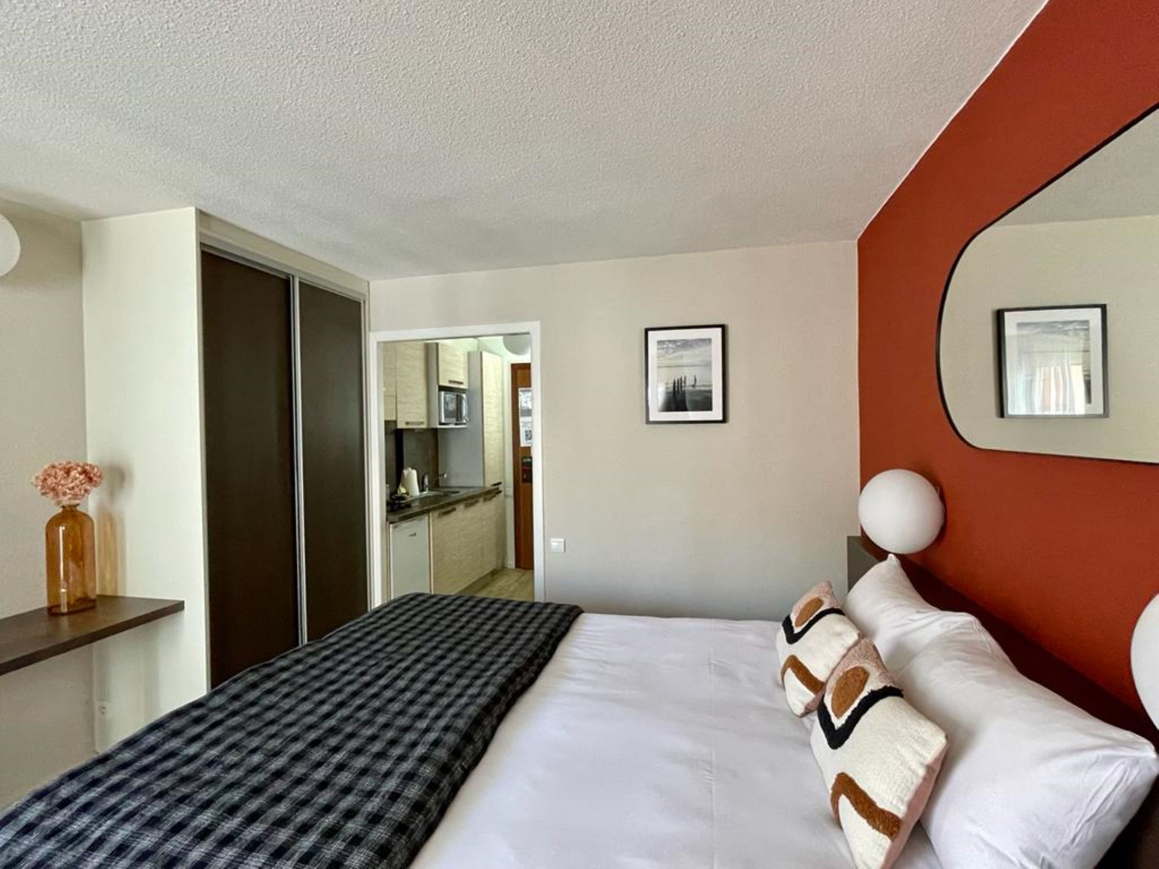 Ein Hotelzimmer mit Bett, Schreibtisch, Spiegel und Blick zur Küche.