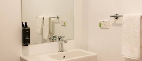 A bathroom with a white sink, a mirror, and a towel rack.
