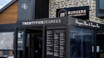Un restaurante con un letrero que indica que ofrece hamburguesas y bebidas alcohólicas, especialidad en preparaciones a 25 grados.
