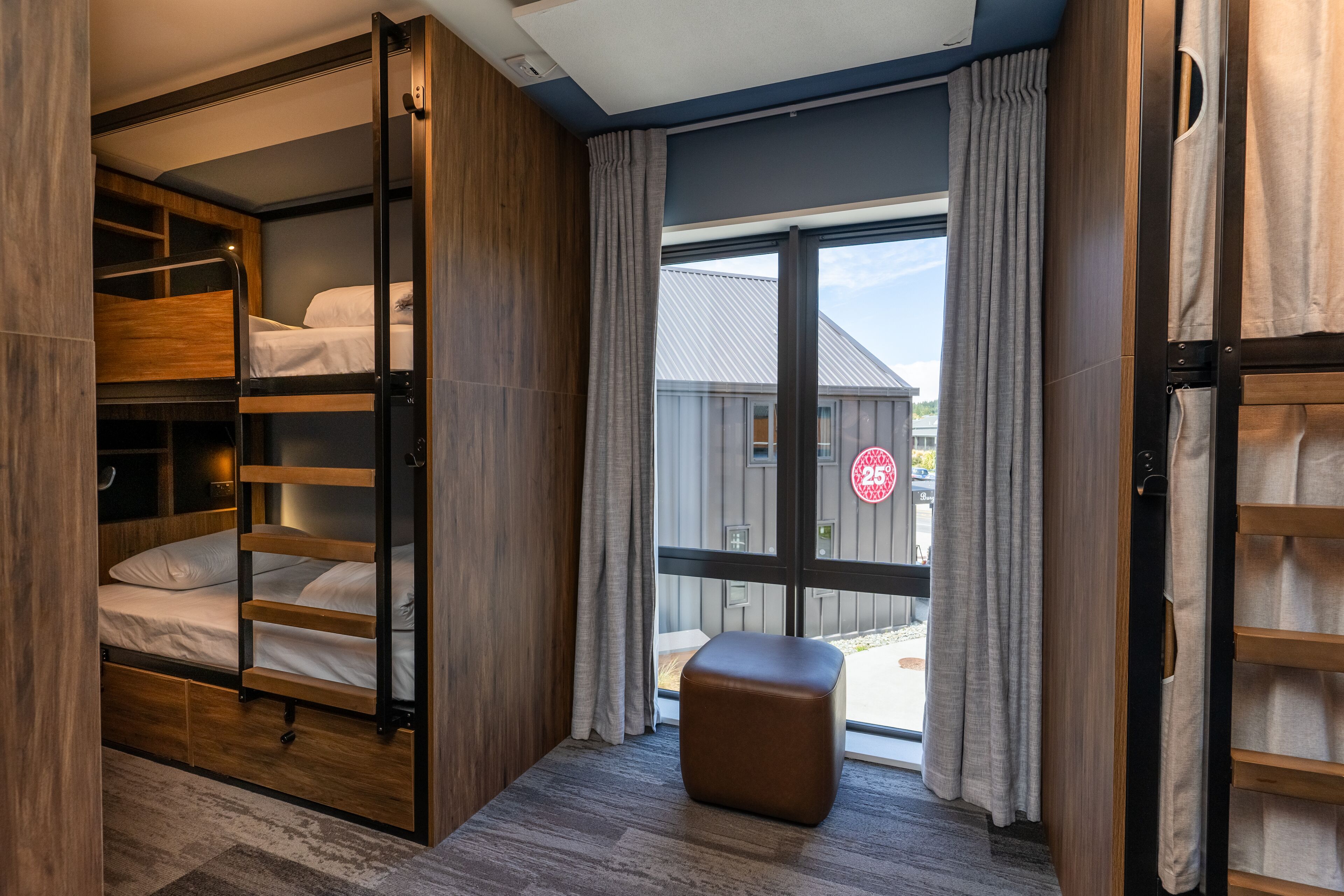 Habitación pequeña con una litera, un taburete y una puerta corredera que da a un balcón.