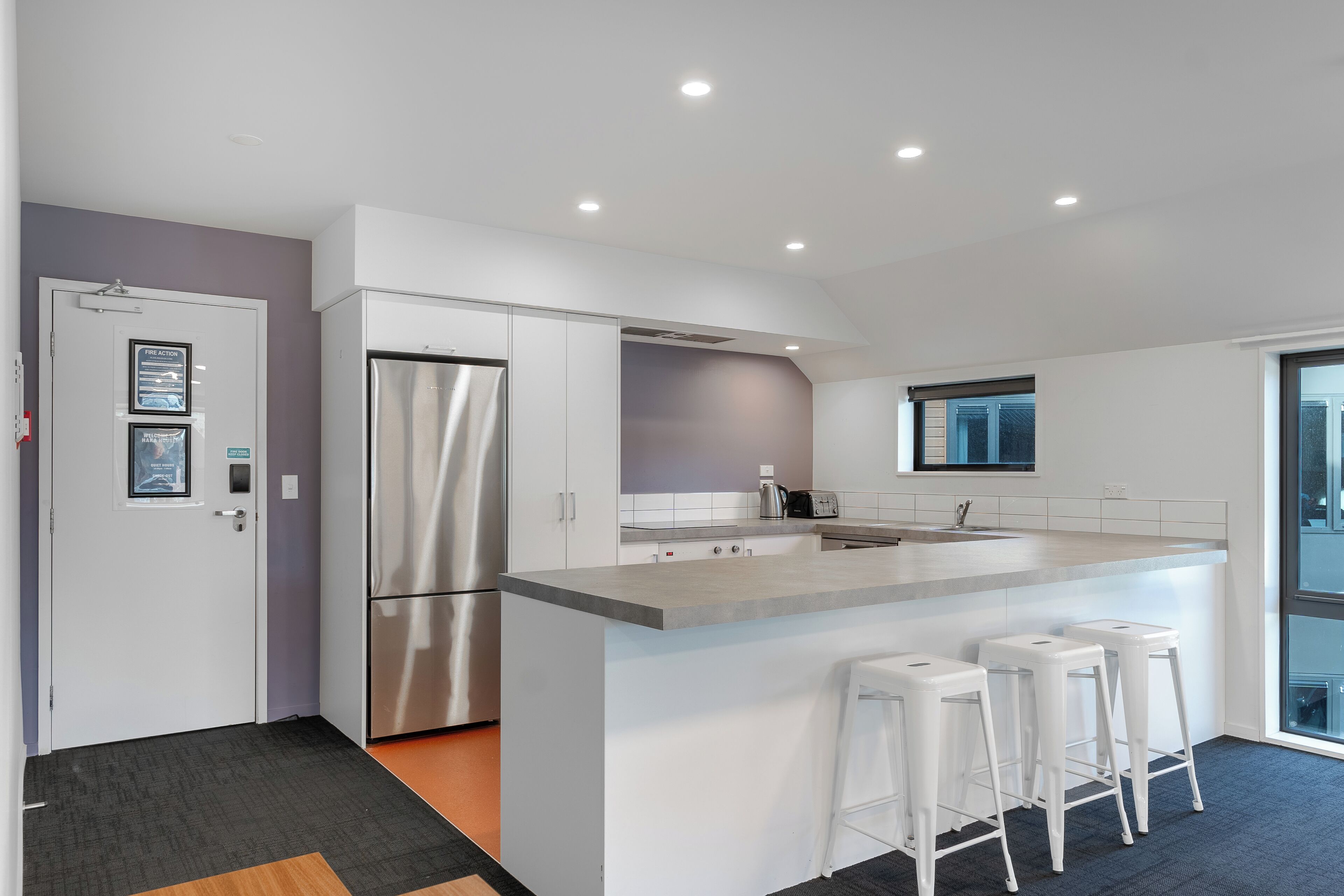 A modern kitchen with a stainless steel refrigerator, a built-in oven, and a large island with bar stools.