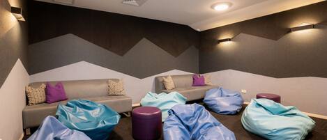 A modern lounge area with sofas and bean bags, a patterned wall, and recessed ceiling lighting.