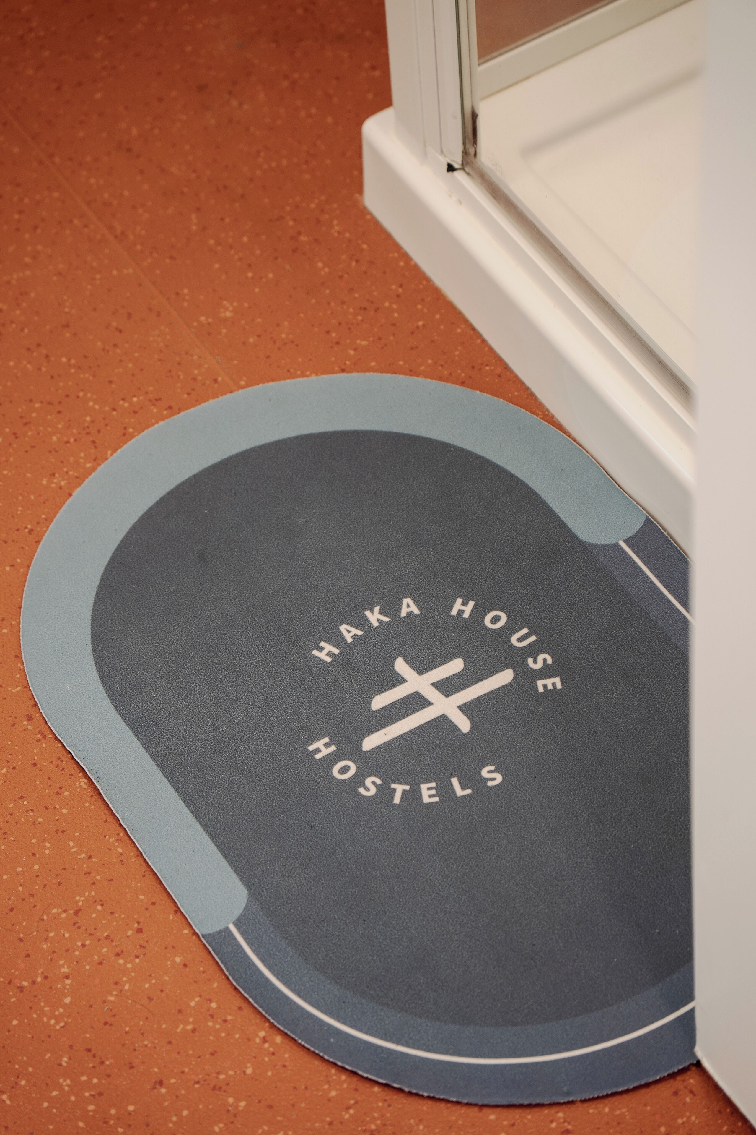 Een mat met de tekst 'Haka House Hostels' op een gestructureerd oppervlak.