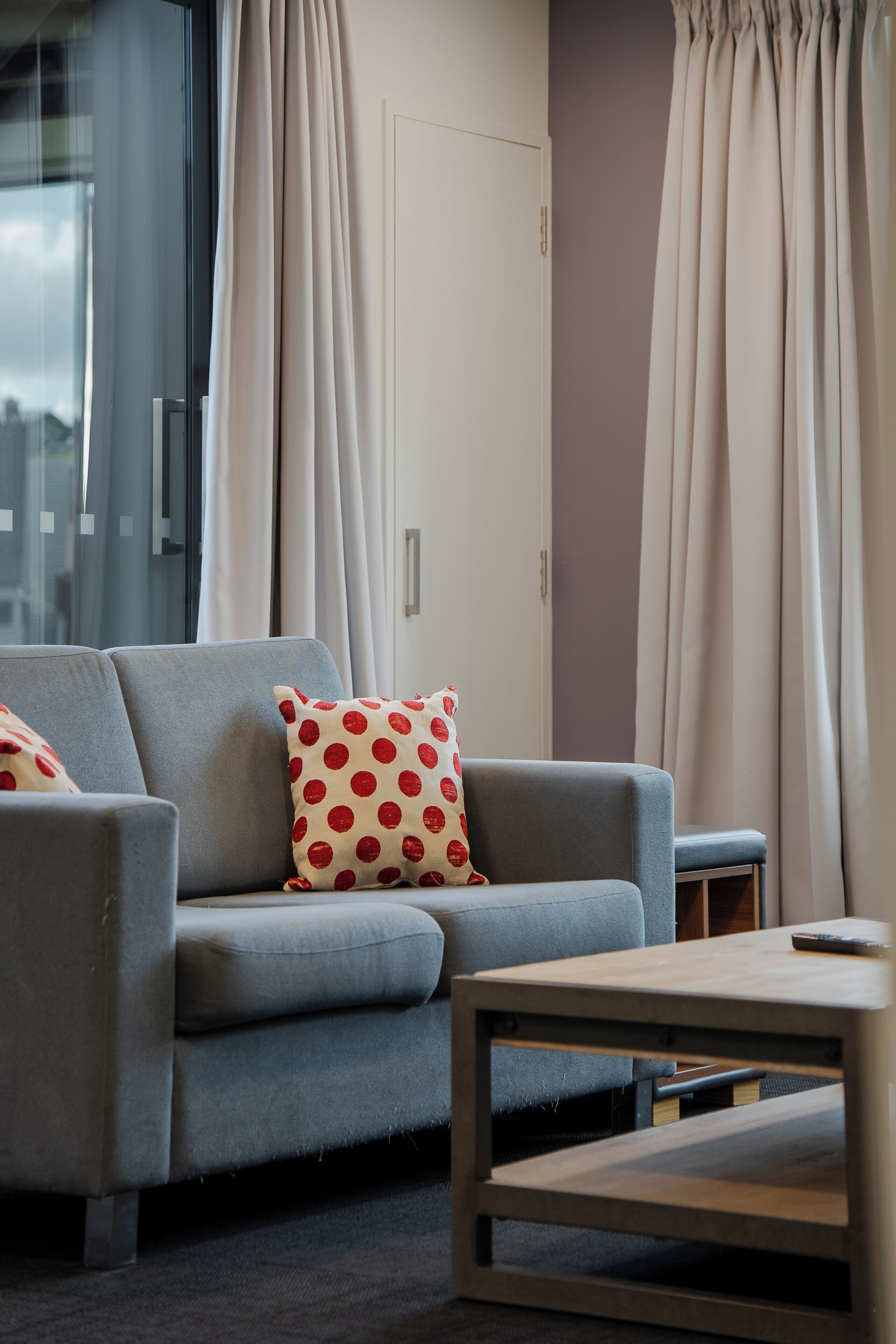 Una sala moderna con un sofá gris, una mesa de centro de madera y un cojín decorativo estampado.
