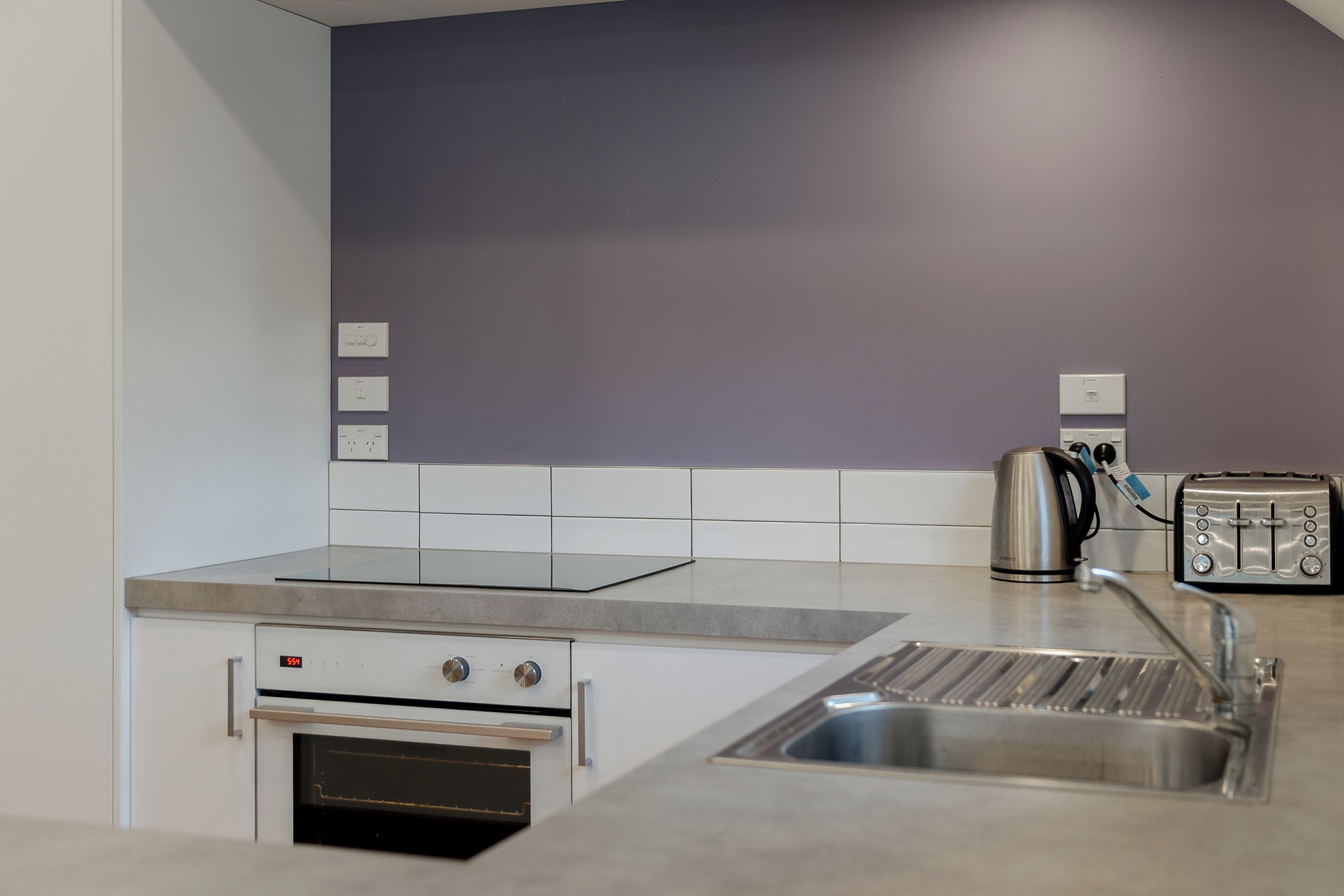 A modern kitchen with a built-in oven, a sink, and a toaster.