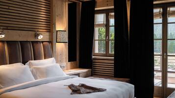A bedroom with a wooden headboard, a large bed with white linens, a bedside table with a lamp, and a window with curtains.