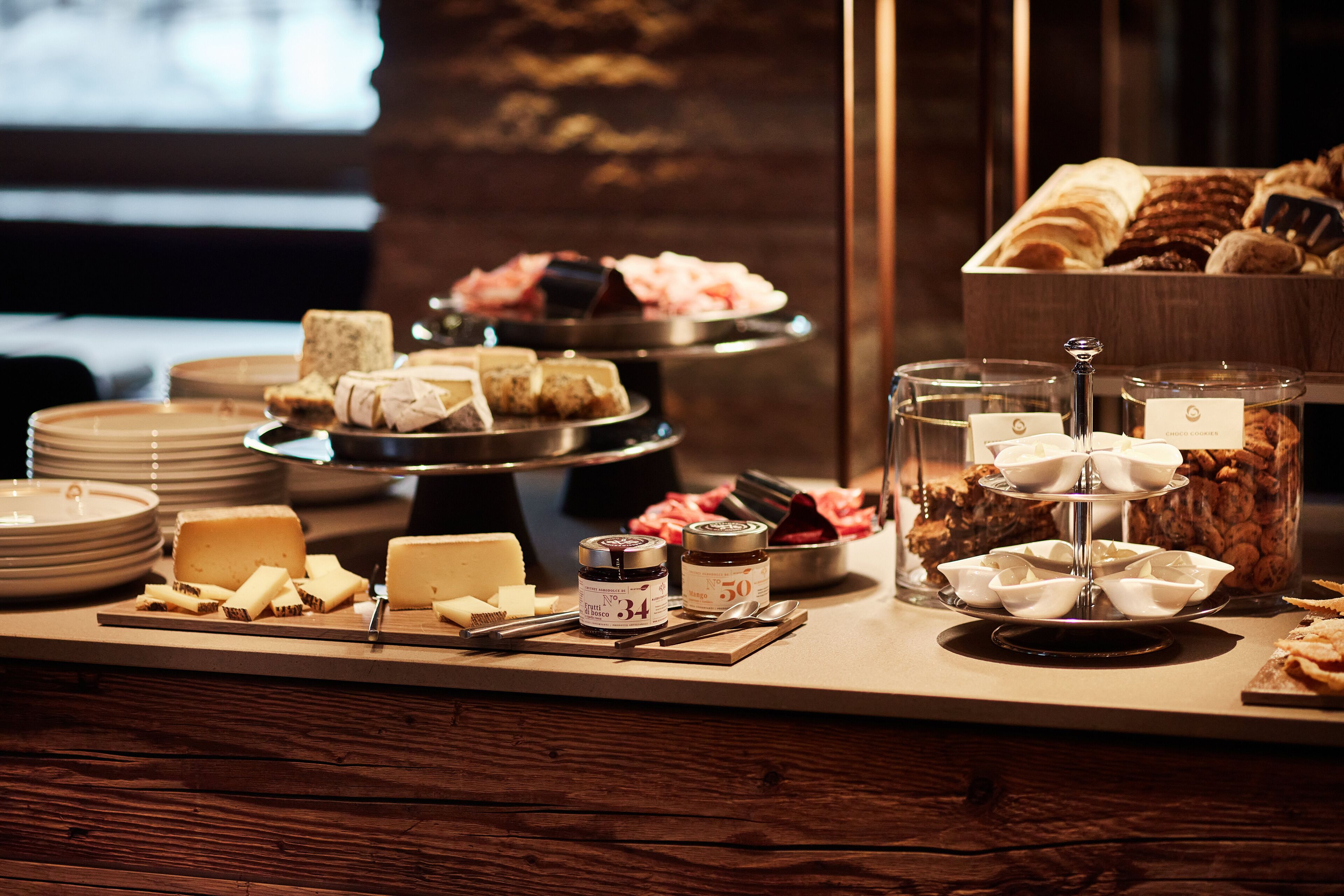 A buffet setup with various cheeses, jams, and pastries.