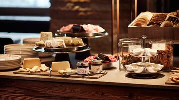 A buffet setup with various cheeses, jams, and pastries.