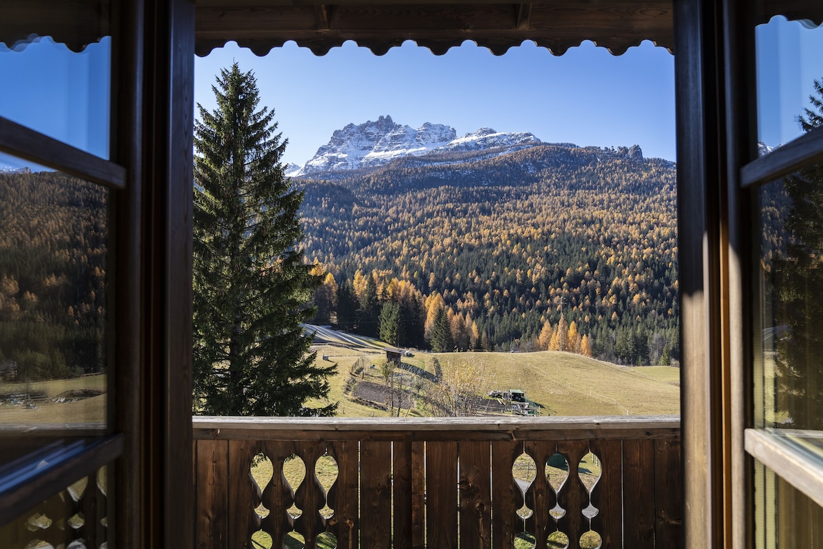 Vista desde un balcón de madera con vistas a un paisaje montañoso bajo un cielo despejado.