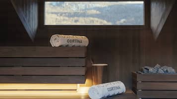 Un sauna con bancos de madera, una ventana con vistas a la montaña y toallas con la etiqueta 'CORTINA'.