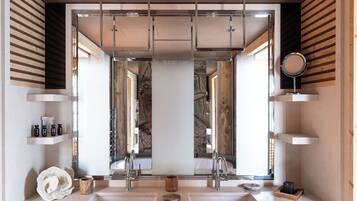 A modern bathroom with dual sinks, a large mirror, and wooden paneling.
