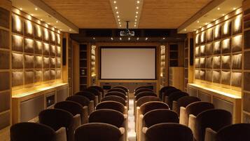 A theater with rows of plush seating, a large screen, and wooden paneling.
