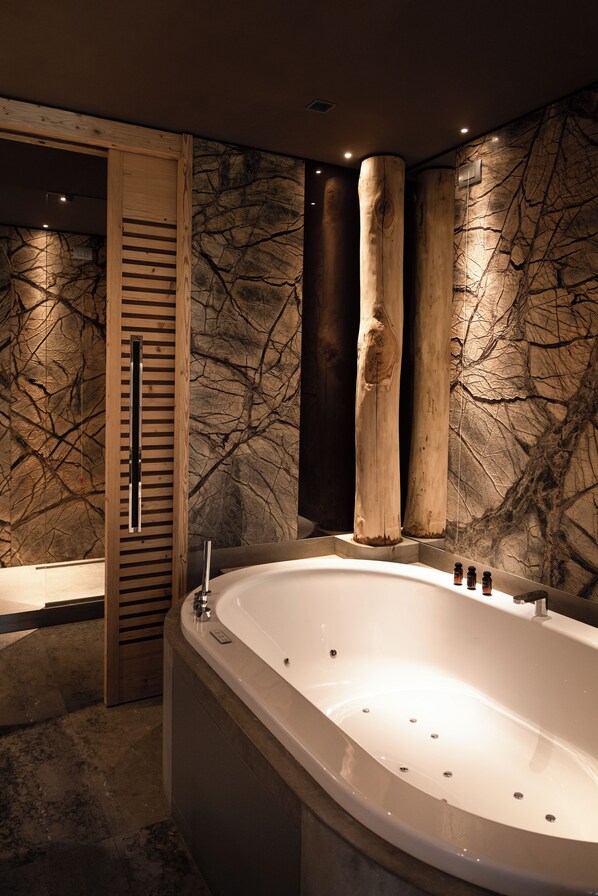 A modern bathroom with a freestanding bathtub, wooden accents, and a textured wall.
