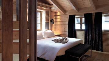 A wooden cabin bedroom with a bed, bench, and a nightstand.