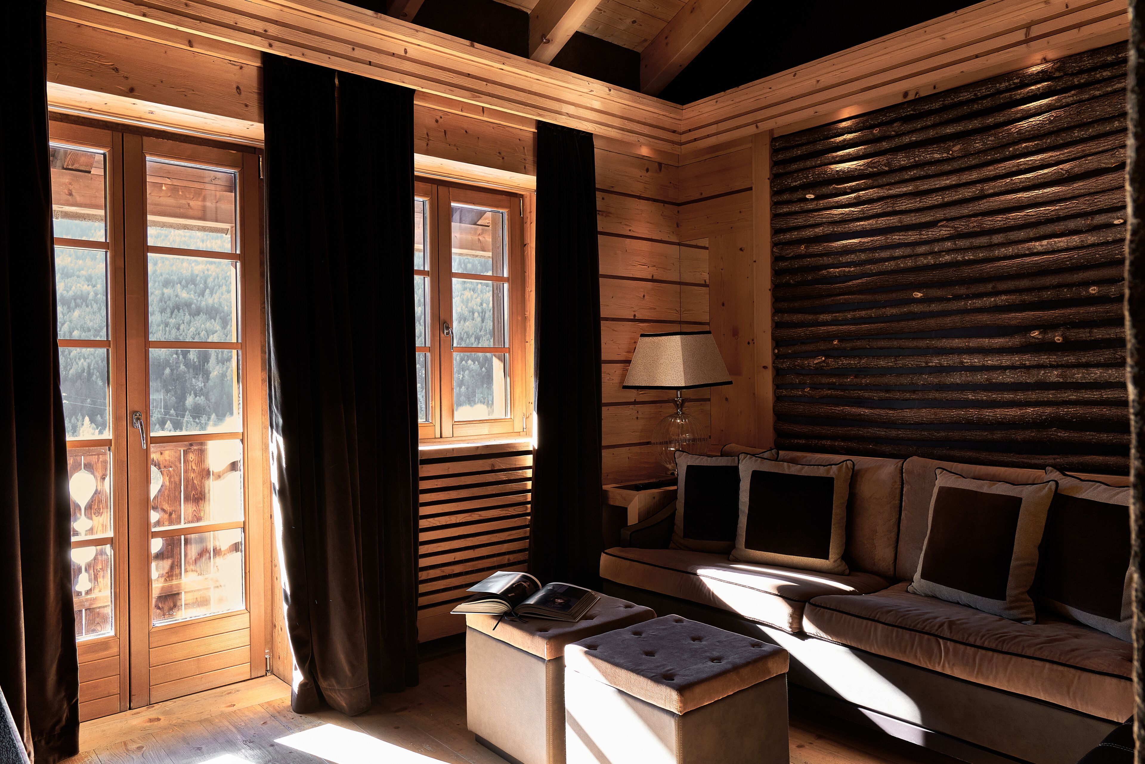 Interior de uma cabana de madeira com um banco, um sofá e uma mesa com um livro.