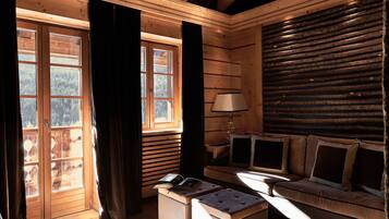 Interior de uma cabana de madeira com um banco, um sofá e uma mesa com um livro.