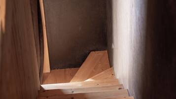 A wooden staircase with a dark wall on one side and a light wall on the other.
