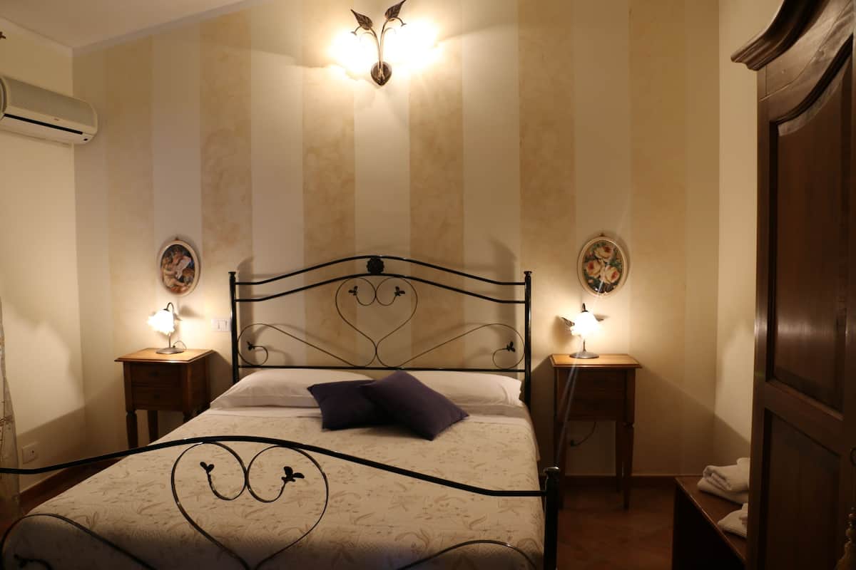 A neatly arranged bedroom with a bed, two bedside tables, and a wall-mounted air conditioner.
