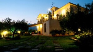 A modern two-story house with a well-lit entrance and a stone pathway leading to the door. - Le Foglie d'Argento (Caltabellotta)