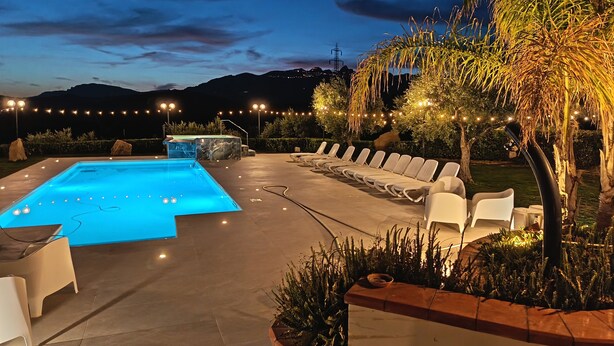 A swimming pool with lounge chairs, a hot tub, and string lights. - Le Foglie d'Argento (Caltabellotta)