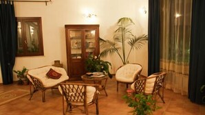 A cozy living room with wicker furniture, a wooden cabinet, and potted plants. - Le Foglie d'Argento (Caltabellotta)