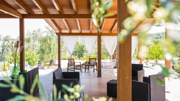 An outdoor patio with wicker furniture and white curtains, surrounded by greenery. - Villa Vesta (Vieste)