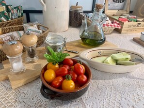 A kitchen counter with various food items and kitchenware, including a bowl of tomatoes, a pitcher of oil, salt and pepper shakers, and a jar of spices. - Villa Vesta (Vieste)