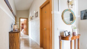 A hallway with a wooden door, a wall-mounted mirror, and a small table with a clock and picture frame. - Villa Vesta (Vieste)