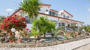 A two-story house with a balcony, surrounded by a garden with various plants and flowers. - Villa Vesta (Vieste)