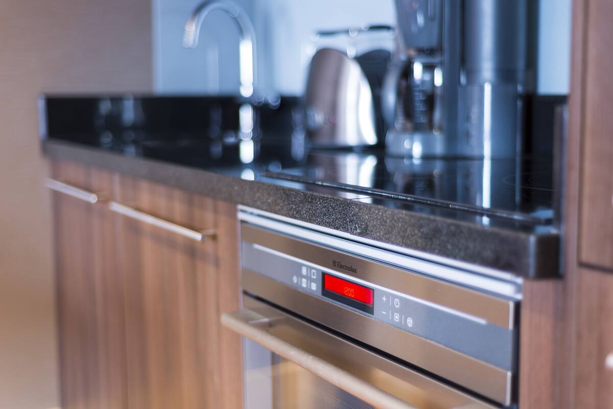 Une cuisine moderne équipée d’appareils électroménagers en acier inoxydable, notamment un four Electrolux doté d’un écran numérique.