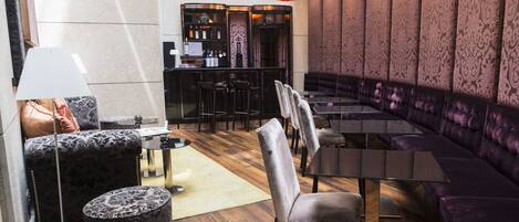 Un espace de détente moderne comprenant un canapé, des fauteuils, une table et un bar.