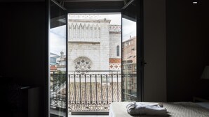 Une chambre dotée d’une grande fenêtre donnant sur un bâtiment historique orné d’un balcon à motifs.