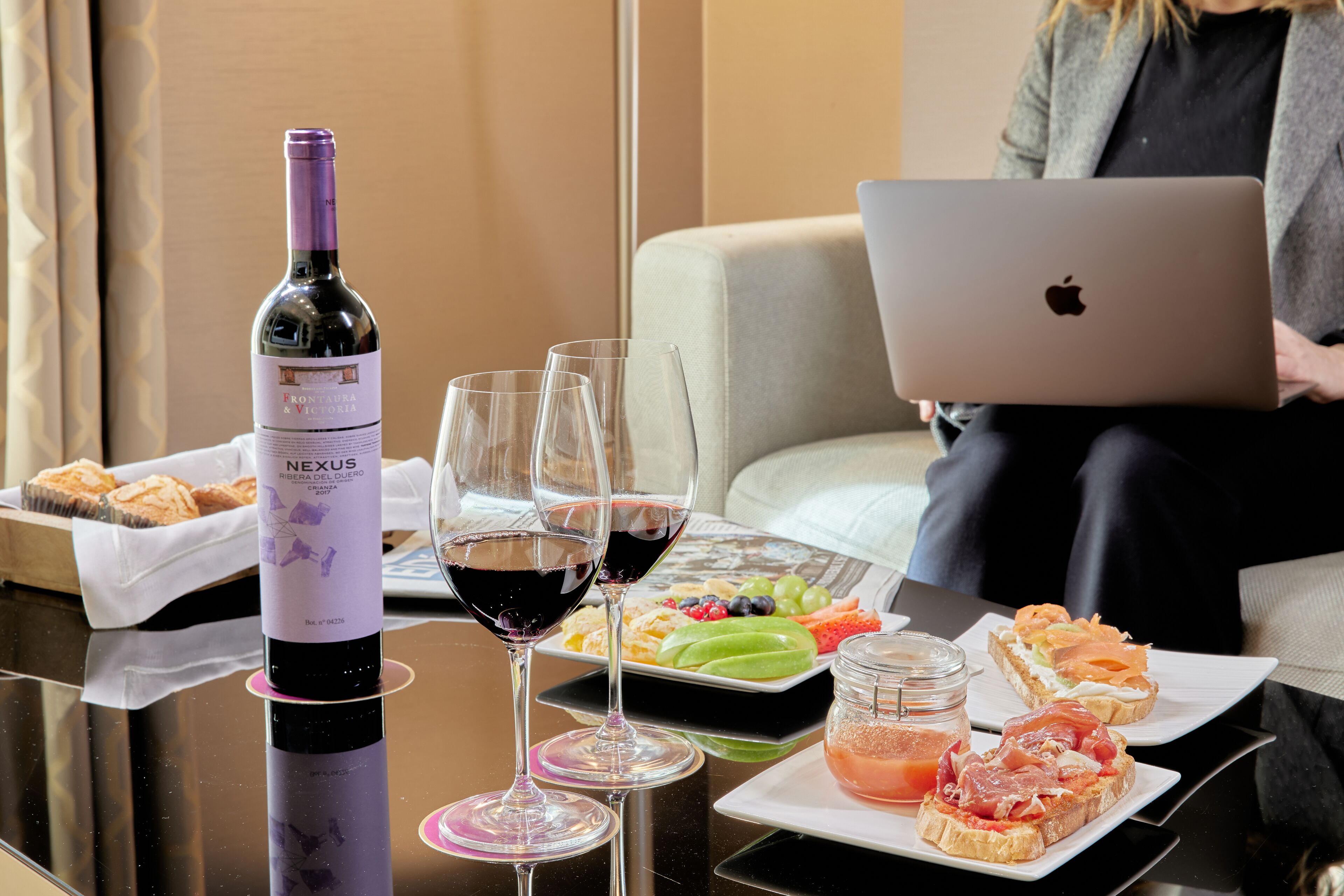 A table with a bottle of wine, glasses, and food items.