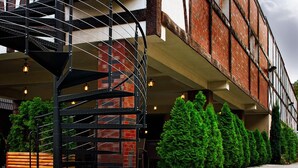 Un bâtiment à la façade en briques, doté d’un escalier en colimaçon et bordé d’une rangée d’arbres verdoyants.