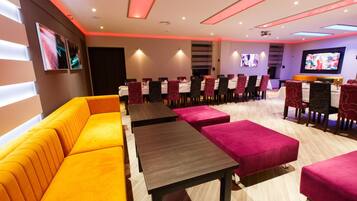 A modern dining area with a long table, multiple chairs, and a sofa.