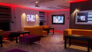 Un espace de détente moderne avec un plancher en bois, des canapés orange et des poufs violets.