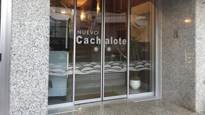 Fachada moderna de un edificio con entrada de vidrio, que muestra el nombre 'Nuevo Cachalote'.