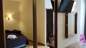 Una habitación de hotel con cama, escritorio, espejo y televisión.