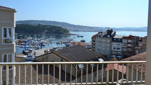 Una marina con barcos, edificios y un paisaje montañoso al fondo.