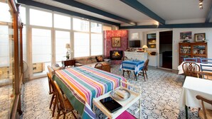 A spacious living area with a large window, a fireplace, a dining table, and a kitchen area. - Casa Rural Mailan (Aia)